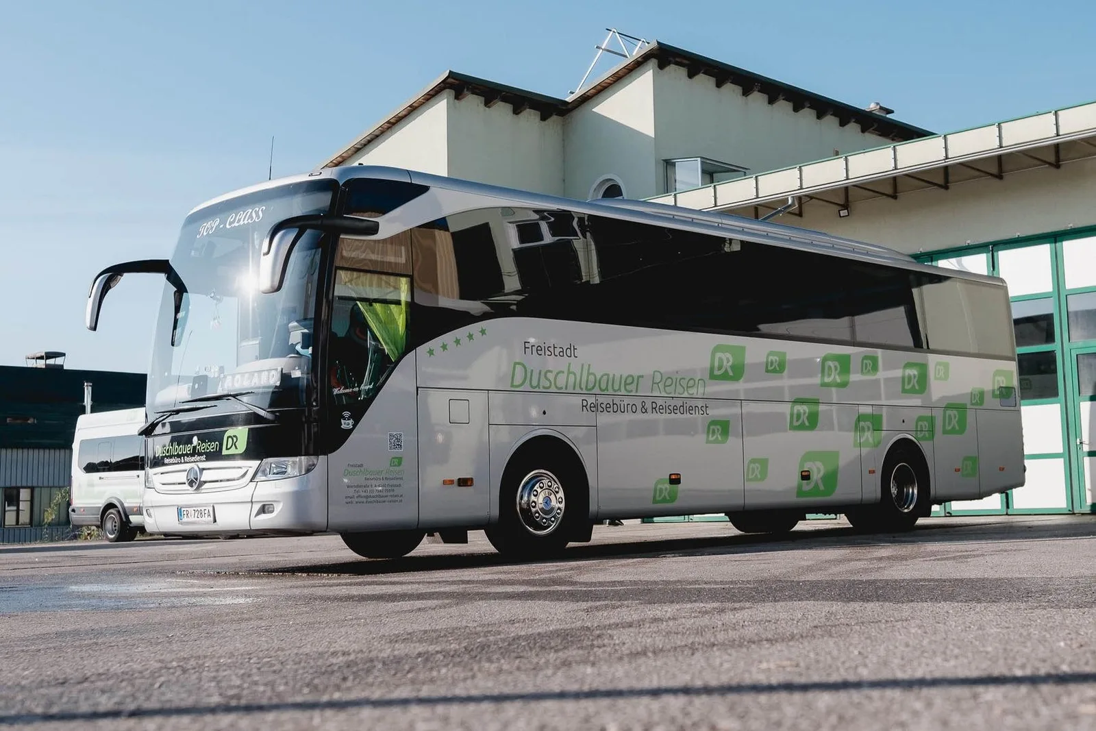 Reisebus Mercedes Tourismo mit Duschlbauer-Beschriftung vor dem Firmengebäude