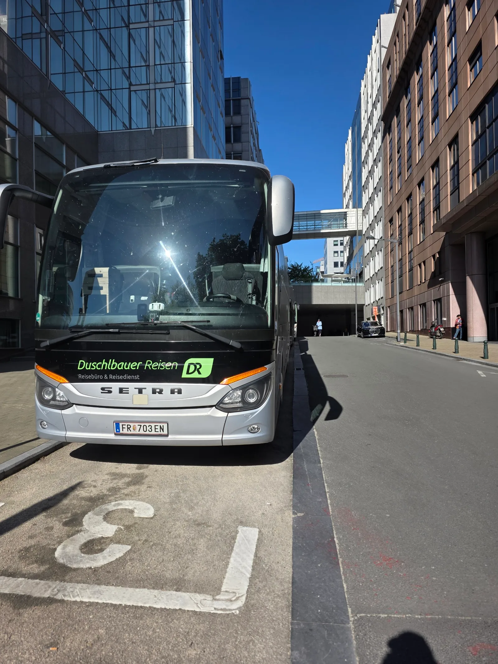 Reisebus von Duschlbauer Reisen auf einem Busparkplatz zwischen hohen Bürogebäuden einer Großstadt